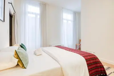 a white bed in a bedroom with windows at The Ghentian Suites by Domani Hotels in Ghent