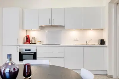 a kitchen with white cabinets and a table and chairs at The Ghentian Suites by Domani Hotels in Ghent