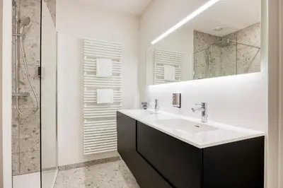 a white bathroom with a sink and a shower at The Ghentian Suites by Domani Hotels in Ghent