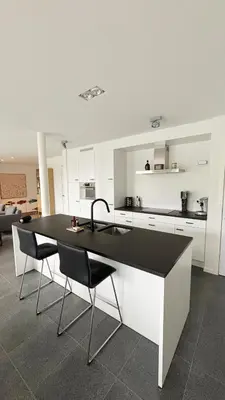 a kitchen with a black and white counter and chairs at Bruggeske aan't bos in Mol