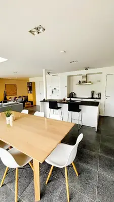 a kitchen and dining room with a wooden table and chairs at Bruggeske aan't bos in Mol