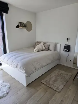 a white bed in a white bedroom with a rug at Tomorrowland Crib in de buurt van Boom in Schelle