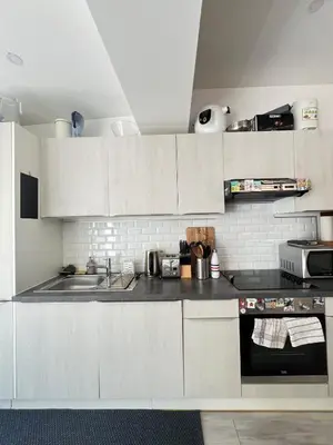 a kitchen with white cabinets and a sink at Tiny House avec terrasse privée, 10 mins du centre in Brussels