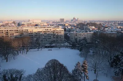 a city with a snow covered field in front of buildings at Apartments overlooking Brussels in Brussels