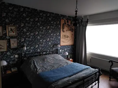 a bedroom with a bed with blue sheets and floral wallpaper at Apartments overlooking Brussels in Brussels