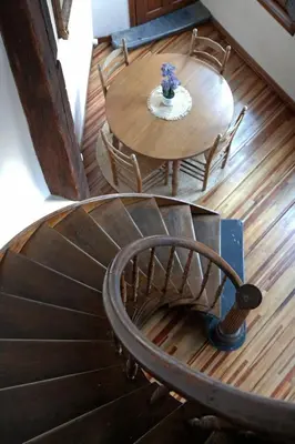 a wooden spiral staircase with a wooden table and chairs at 18de-eeuwse woning in het hartje van Gent in Ghent