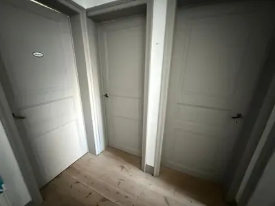 an empty hallway with two white doors and a wooden floor at Dock Suites in Ghent