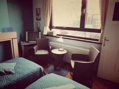 a room with two beds and a table and a window at B&B Lieven Bauwens in Ghent