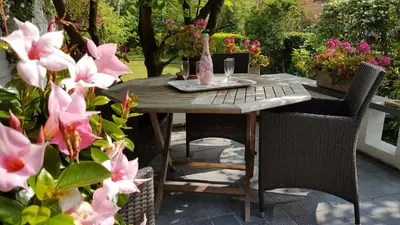 a wooden table with chairs and flowers on a patio at B&B Lieven Bauwens in Ghent