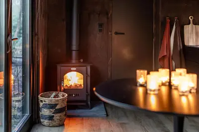 a wood stove in a room with a table with candles at Cabins in the woods with wellness in Brasschaat