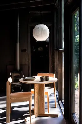 a table and chairs in a room with a lamp at Cabins in the woods with wellness in Brasschaat