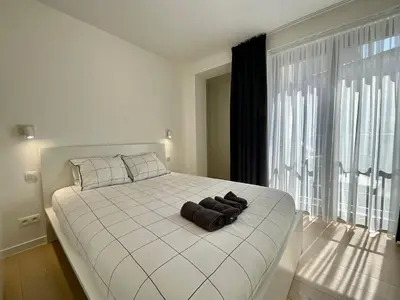 a bedroom with a white bed with a large window at Chapeliers 34 in Brussels