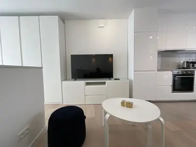 a white kitchen with a white table and a tv at Chapeliers 34 in Brussels