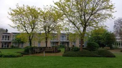 a building with two trees in a yard at Appartement dans parc