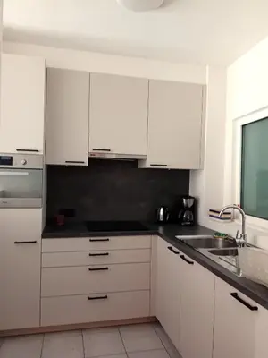 a white kitchen with white cabinets and a sink at Appartement dans parc