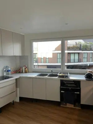 a kitchen with white cabinets and two windows at Toverpoort - Seperate room in shared apartment in Ghent