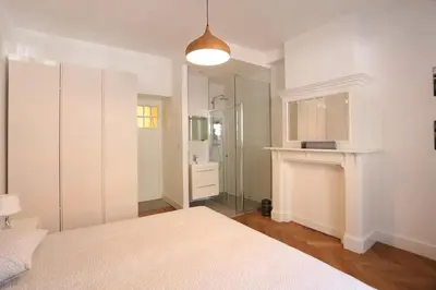 a white bedroom with a bed and a mirror at Belliard flat in Brussels