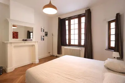 a bedroom with a white bed and a fireplace at Belliard flat in Brussels