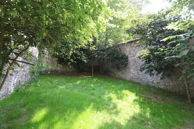 a garden with a brick wall and green grass at Belliard flat in Brussels