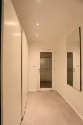 a hallway with white walls and a mirror at Belliard flat in Brussels