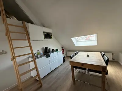 a kitchen with a loft bed and a wooden table at Dock Loft in Ghent