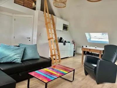 a living room with a black couch and a ladder at Dock Loft in Ghent