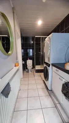 a bathroom with a toilet and a washer and dryer at Tomorrowland guest appart in Boom