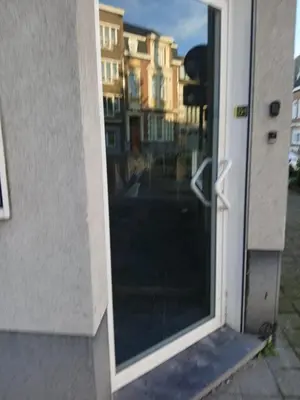 a glass door with a reflection of a building at Tomorrowland guest appart in Boom