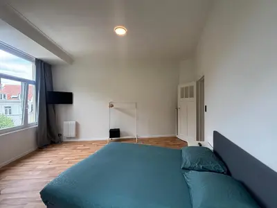 a bedroom with a blue bed and a large window at Basilique Brussels 2 in Brussels