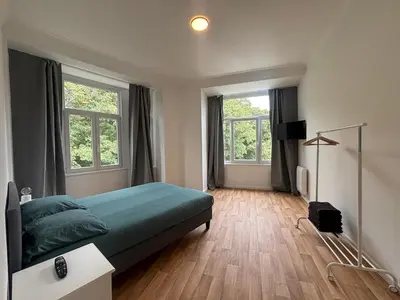 a bedroom with a green bed and two windows at Leopold Brussels 6 in Brussels