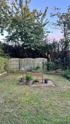 a wooden bench sitting in a yard next to a fence at Cozy apartment with garden in Ghent