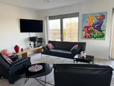 a living room with black leather furniture and a flat screen tv at DoK9 in Ghent