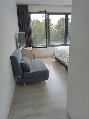 a room with a chair and a bed and windows at Tomorrowlandhome Boom in Boom