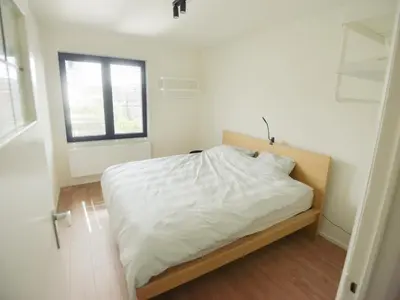 a bedroom with a bed with white sheets and a window at Top floor apartment at Saint Peters Station in Ghent