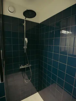 a bathroom with a shower with blue tiles at Top floor apartment at Saint Peters Station in Ghent