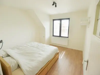 a white bedroom with a bed and a window at Top floor apartment at Saint Peters Station in Ghent