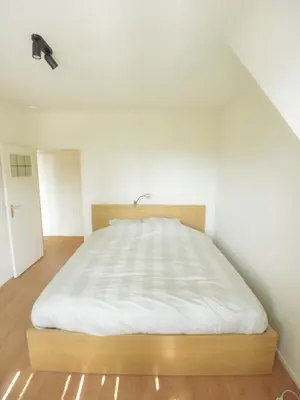 a bed in a room with a white wall at Top floor apartment at Saint Peters Station in Ghent
