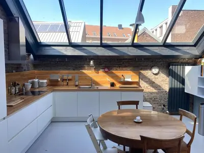 a kitchen with a wooden table and a large window at The Urban Loft in Brussels West in Brussels