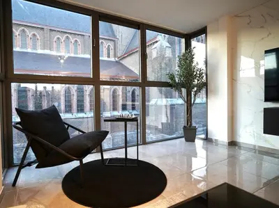 a chair in a room with a large window at Chic Loft Facing Neo-Gothic Church in Ghent