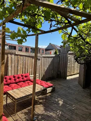 a red couch sitting on a wooden deck at Loft Cosy avec billard et à 10 minutes de l'aéroport de Zaventem in Machelen