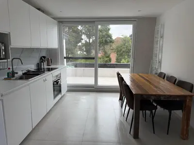 a kitchen with a wooden table and a large window at Beautiful house &parking space in Leuven