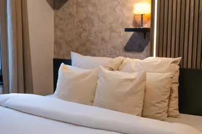 a bed with white pillows on top of it at Spacious & Stylish 3 adjacent Bedrooms Stay in Central Ghent in Ghent