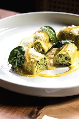 a plate of food with spinach on a table at Bellavista Luxe Apartment with Leie View in Ghent