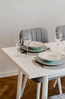 a white dining room table with plates and wine glasses at Bellavista Luxe Apartment with Leie View in Ghent