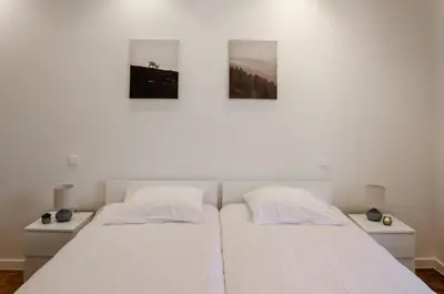 two beds in a white room with two night stands at La Veduta - Luxe Apartment with Leie View in Ghent
