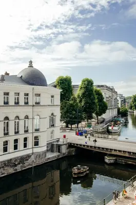 a building next to a river with a bridge at La Veduta - Luxe Apartment with Leie View in Ghent