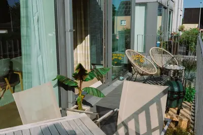 a balcony with chairs and a table and a plant at La Petite Foret Contemporary Apartment in Halle in Halle