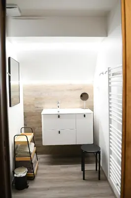 a bathroom with a white sink and a stool at Vakantiewoning Nijkenhof in Ninove