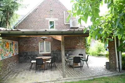 a patio with tables and chairs in front of a brick building at Vakantiewoning Nijkenhof in Ninove