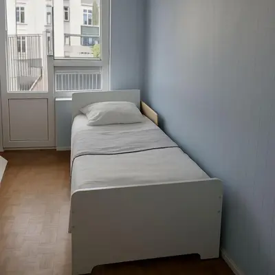 a small bed in a room with a window at Belgielei business apartment in Antwerp